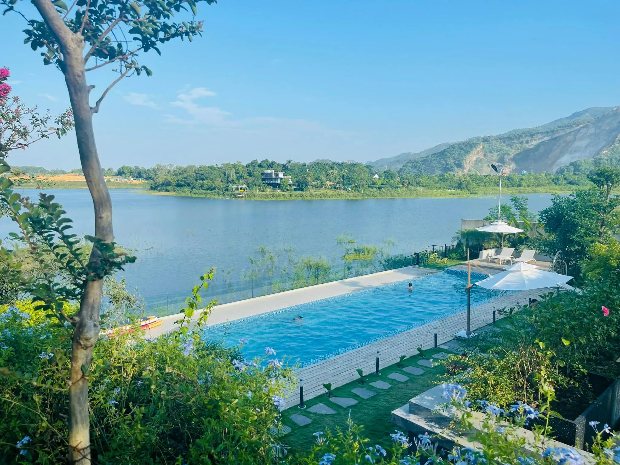 Hồ bơi đặt sát mặt hồ, các cấp sân vườn và lối đi đá tại villa nghỉ dưỡng Đồng Chanh Hòa Bình do Archiindex thiết kế