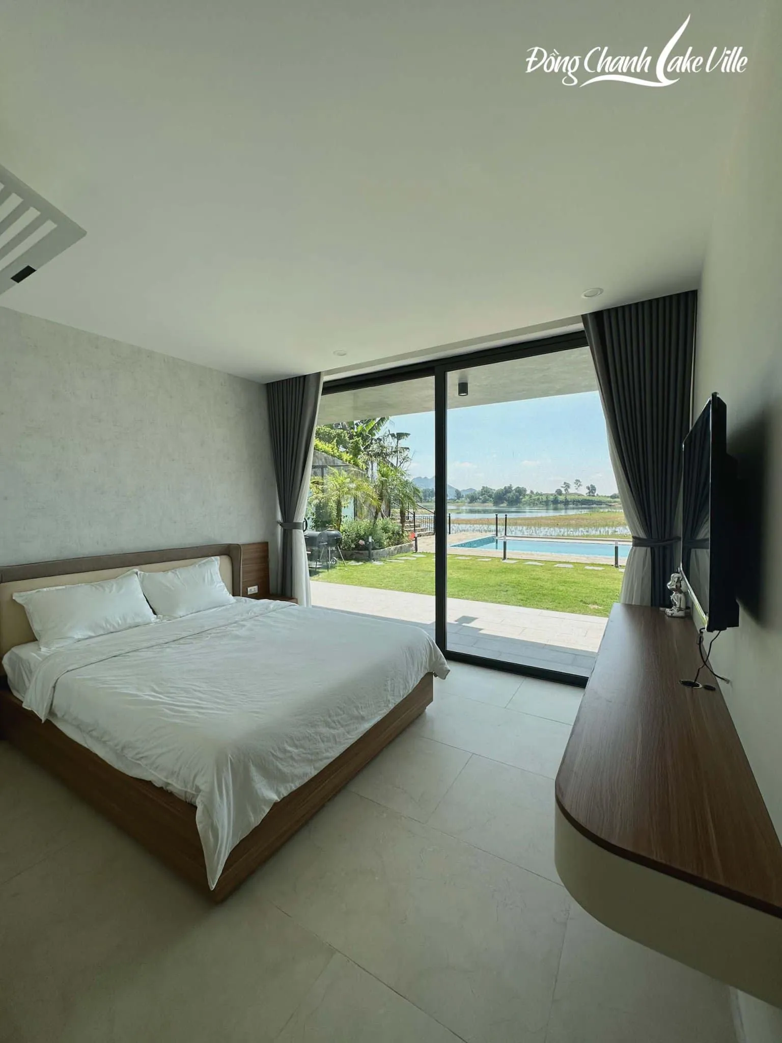 Phòng ngủ villa nghỉ dưỡng mở thẳng ra sân cỏ, hồ bơi và hồ Đồng Chanh, thiết kế sẵn sàng cho thuê